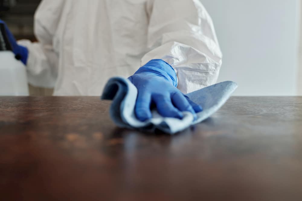 Gloved hands sanitise a table as Sydney works to contain COVID-19 outbreaks.