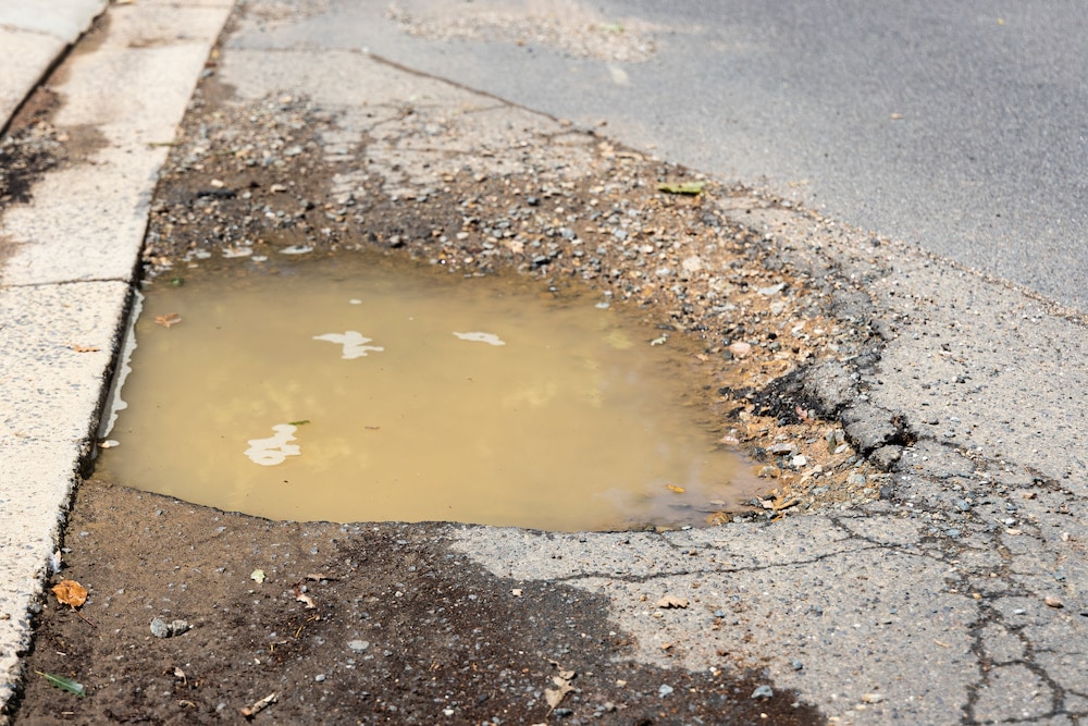 A pothole in Canberra filled with muddy water, an outstanding Fix My Street request.