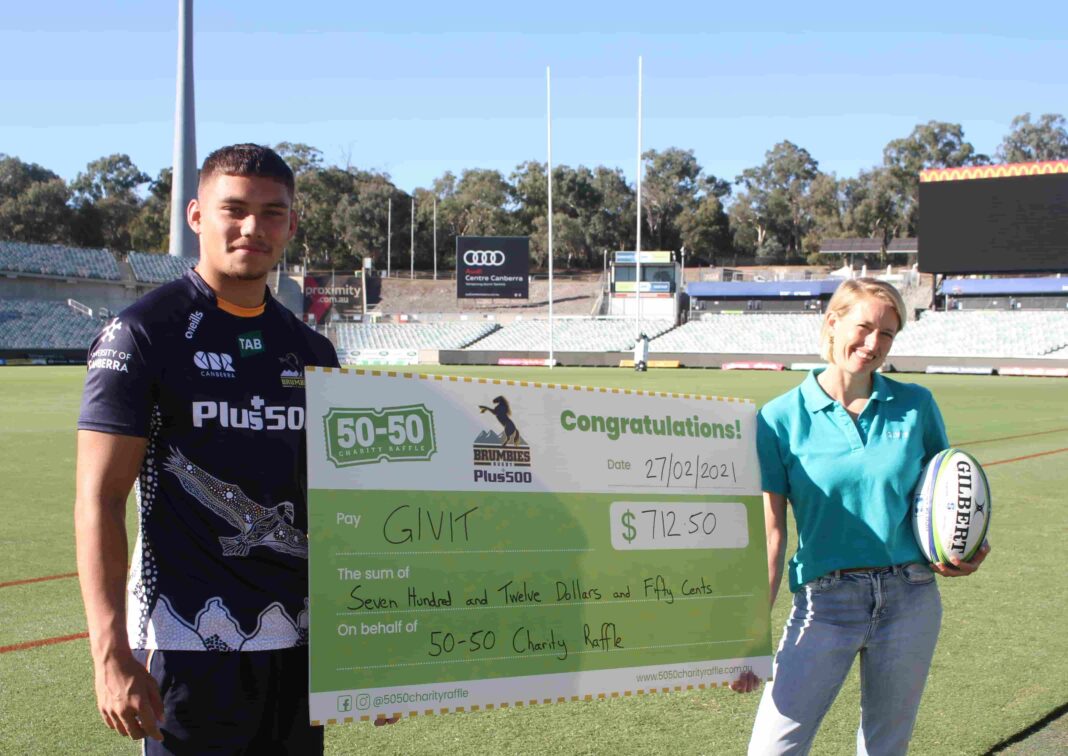 a Brumbies rugby union player and a woman from the GIVIT charity holding a big cheque for $712.50