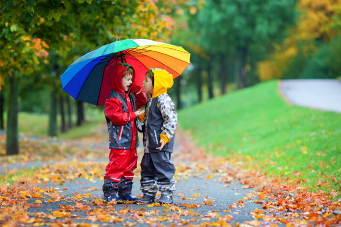two kids in the rain with an umbrella