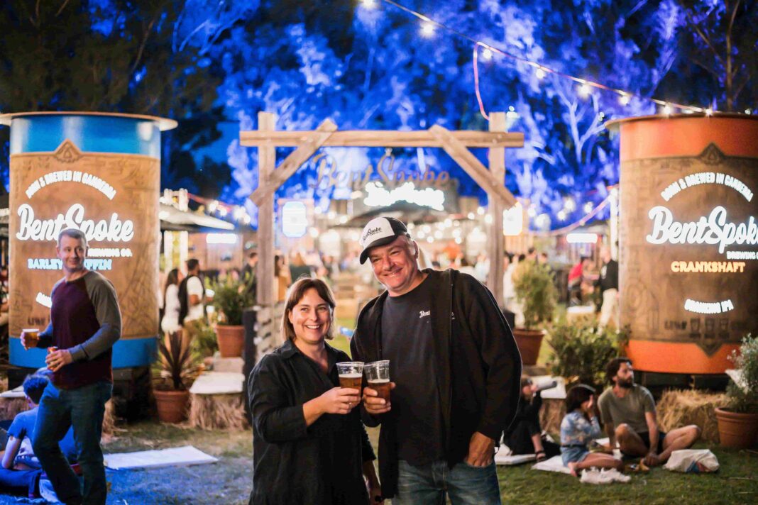 Woman and man with beers in a picturesque beer garden at night