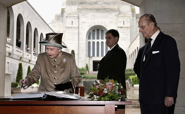 Queen Elizabeth signs visitor book at the Australian War Memorial as Prince Philip looks on