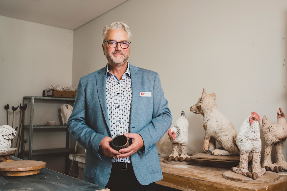 smiling grey haired man in a ceramic art gallery
