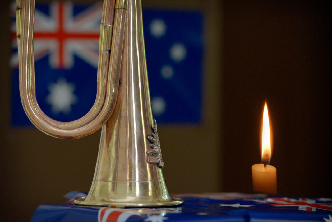 a military bugle and candle in front of an Australian flag
