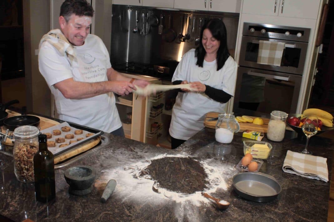 woman and man stretching dough while baking in a messy kitchen