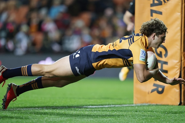 rugby player in yellow jersey and navy shorts diving across the line to score a try