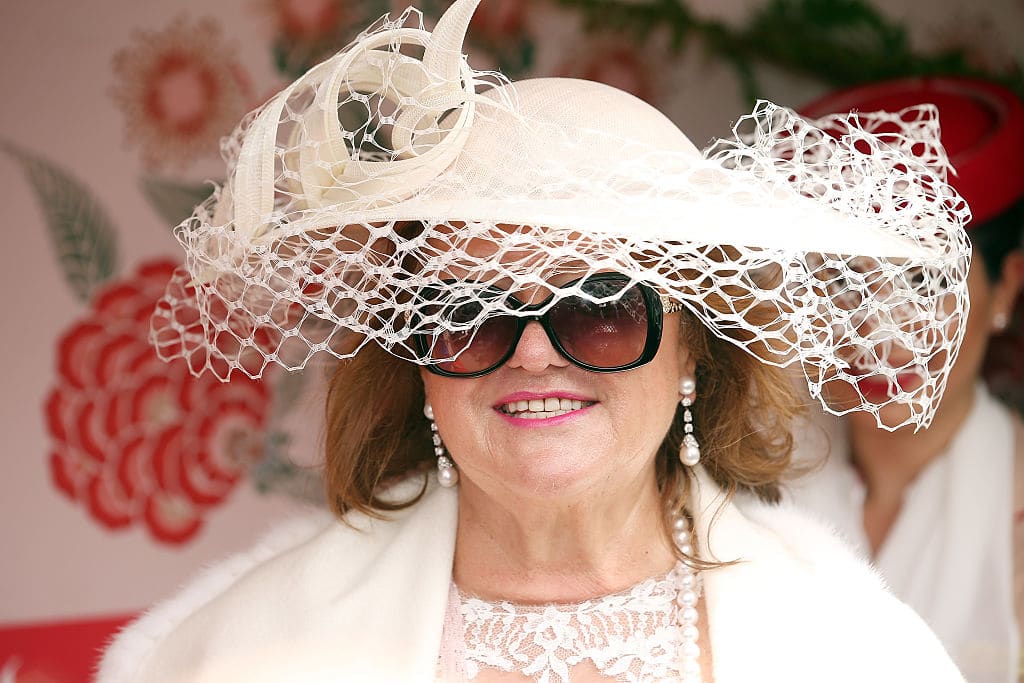 Australia's wealthiest person, mining magnate Gina Rinehart, a middle aged woman in a white outfit with big white hat and sunglasses at the Melbourne Cup