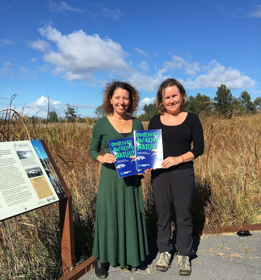 Two women in a nature park holding a guidebook to nature in the Australian Capital Territory