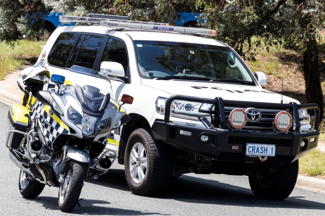 A white police motorbike parked alongside a white ACT police 4WD with bullbar and 'CRASH1' numberplate