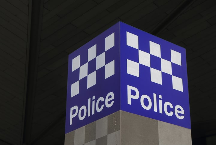 3D blue and white check Police sign outside police station at night