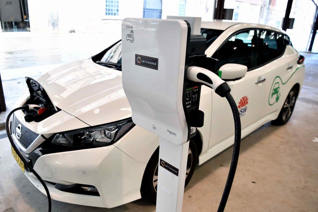 white electric vehicle plugged into a charging station