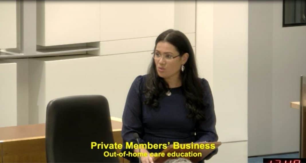 professional woman with dark hair and glasses speaking in the ACT Legislative Assembly chambers