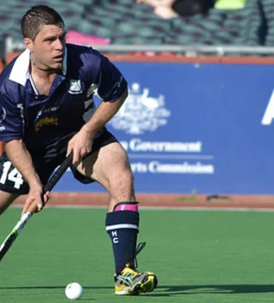 male field hockey player in dark blue kit ready to strike the puck