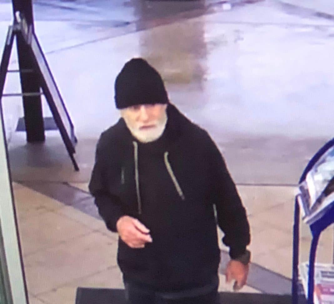 CCTV footage of man with white beard wearing black beanie and black hoodie at a shopping centre