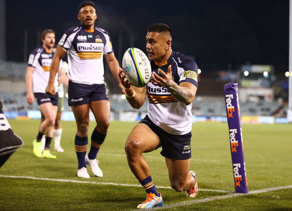 Pacific Islander rugby player in Brumbies kit raising the ball after scoring a try