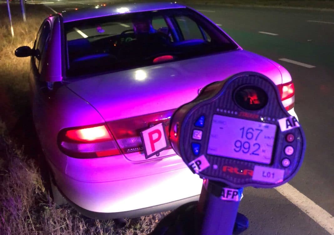 hand-held speed detector showing 167 km/h on it behind a white sedan displaying a P plate