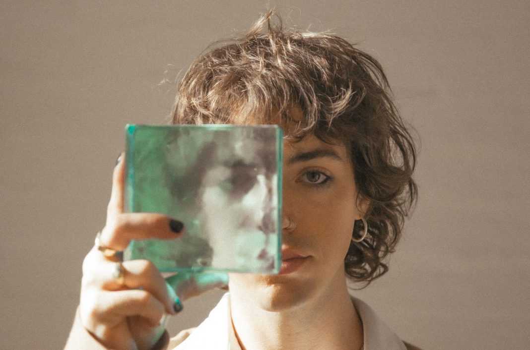 Young male indie music performer looking at camera through a square of glass