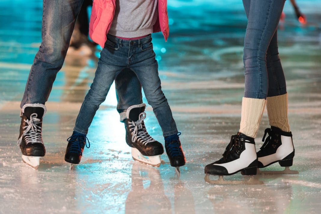 Three pairs of feet ice-skating
