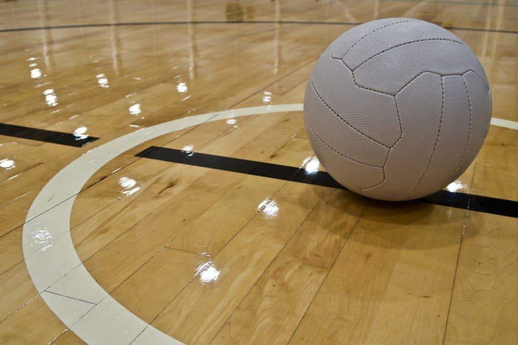 white netball sitting in centre circle of deserted indoor netball court