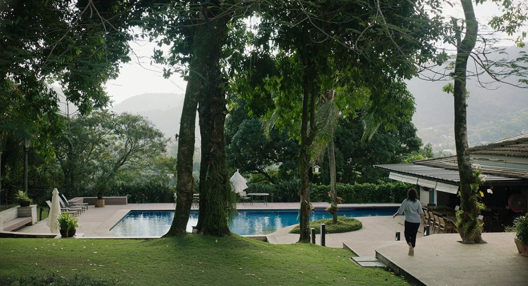 wealthy woman walking near outdoor pool set in beautifully landscaped gardens in Brazil