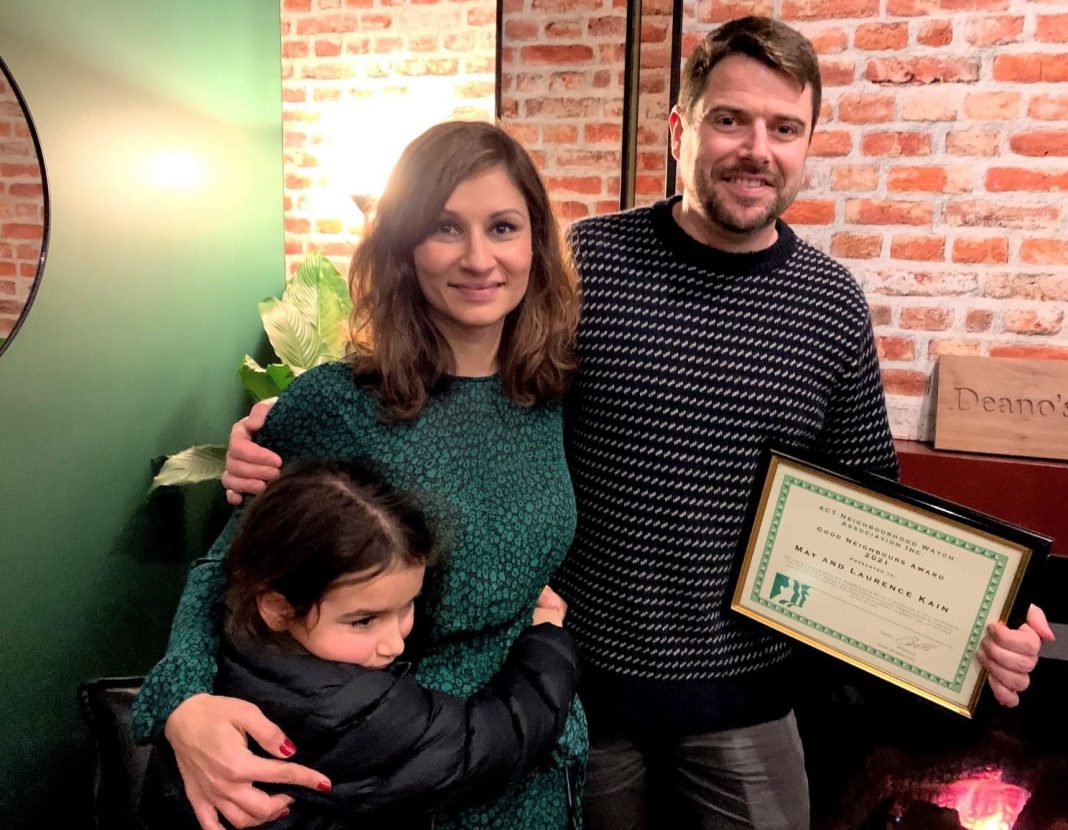 Smiling heterosexual couple with young daughter holding a Neighourhood Watch award