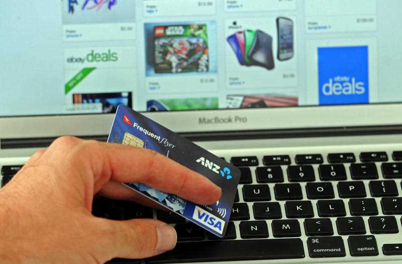 hand holding credit card hovering over keyboard of laptop open at online shopping site