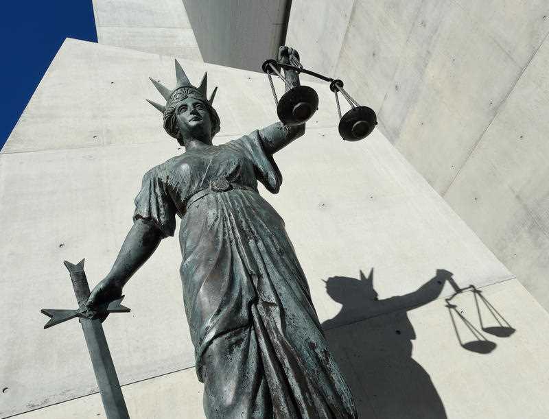 A statue of Themis, the Greek God of Justice stands outside a courthouse