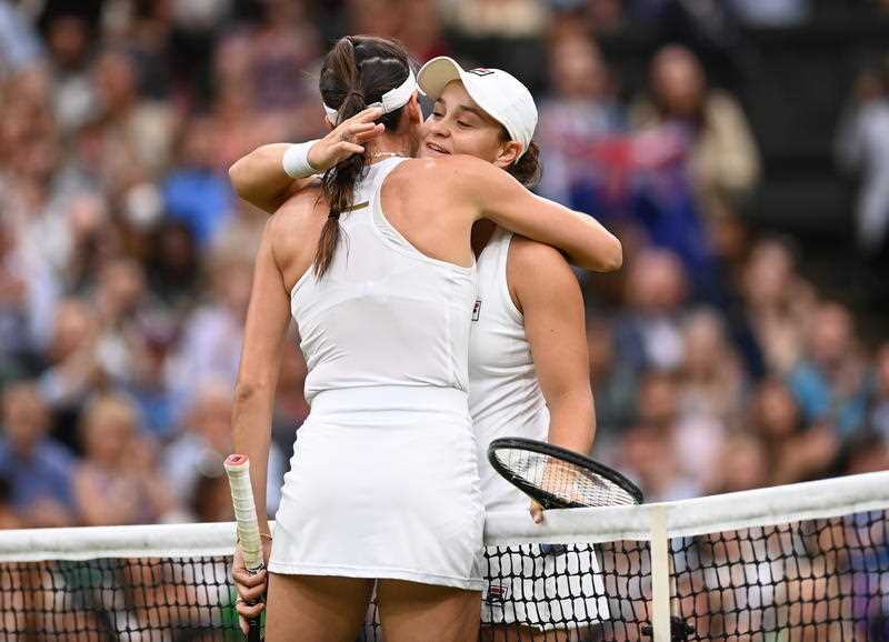 Female Australian tennis player Ash Barty being hugged by compatriot Alja Tomljanovic over the net at Wimbledon