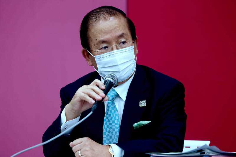 a Japanese business man wearing a face mask speaks into a microphone