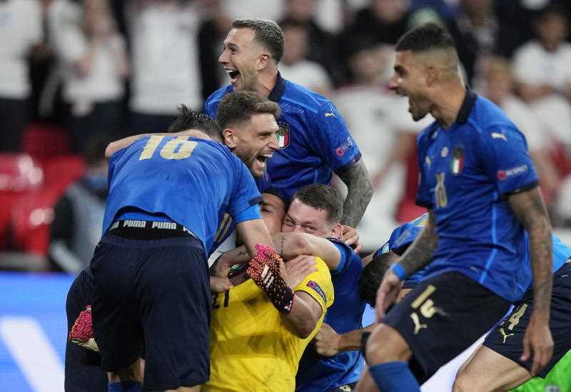 5 Italian male footballers in blue hugging their goalkeeper in yellow