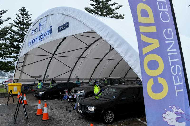 Health workers dressed in Personal Protection Equipment (PPE) conduct testing at the St Vincent’s Drive-Through COVID-19 testing clinic at Bondi