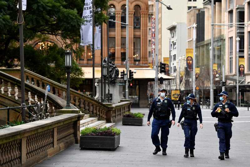 3 NSW Police wearing face masks patrol on George Street in the central business district in Sydney