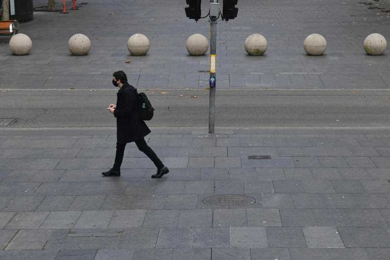 A lone pedestrian wearing face mask walks along Martin Place in the central business district in Sydney