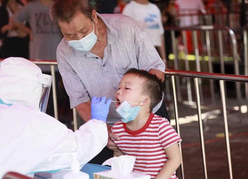 Young boy accompanied by adult wearing mask has covid test in China