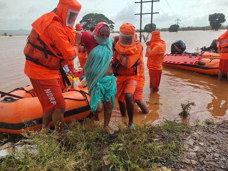 A handout photo made available by India's National Disaster Response Force (NDRF) shows NDRF personnel rescuing stranded villagers from flooded areas at Balinge village, Kolhapur district, Maharashtra state, India