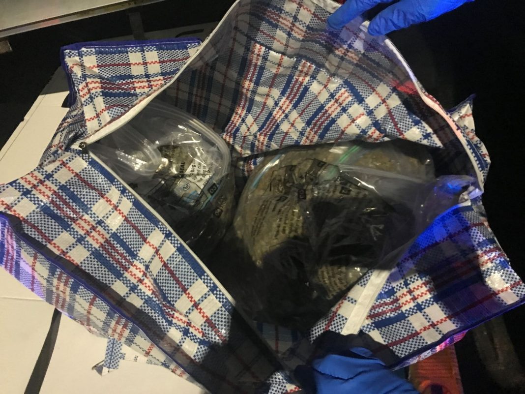 large travel bag full of plastic bags of dried cannabis