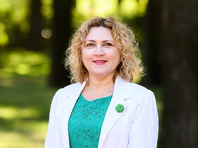 young blond haired female Greens politician Emma Davidson in green shirt and white jacket