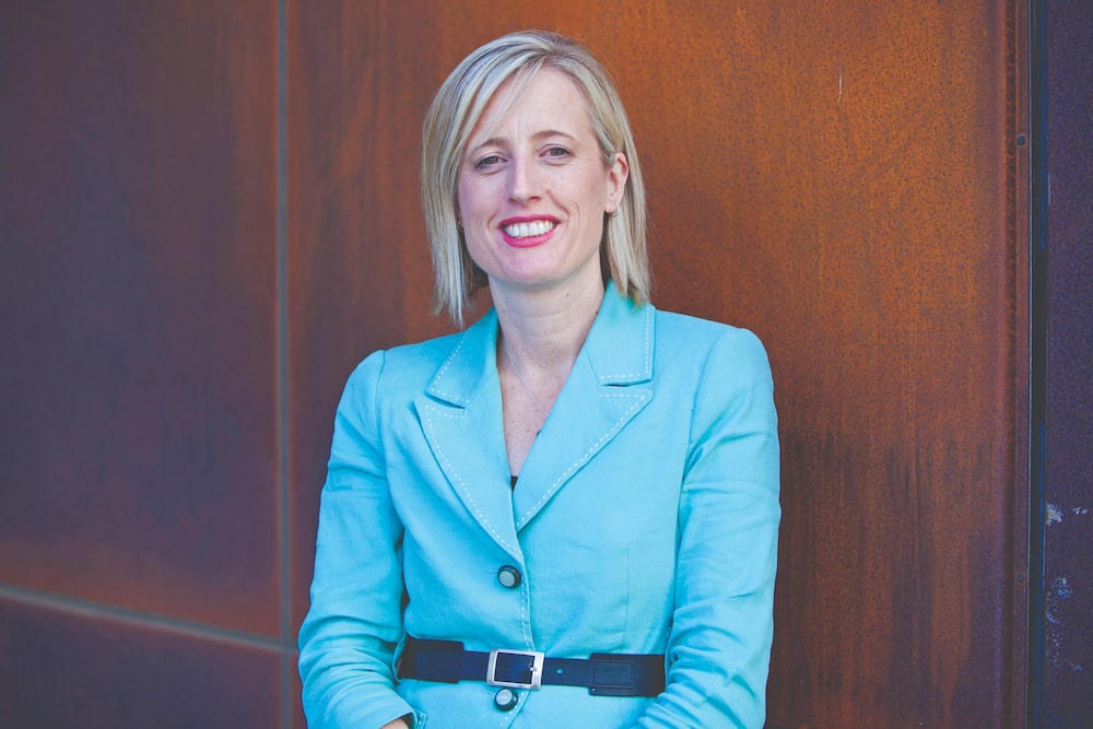 Senator Katy Gallagher, a middle-aged female politician, wearing a blue jacket and smiling
