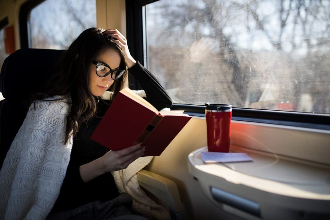 woman reading a book on a train