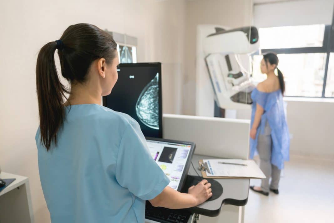 nurse operating equipment while a female patient undergoes a mammogram