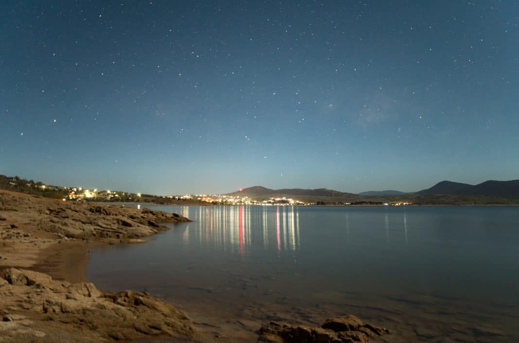 distant shot of city lights of NSW town of Jindabyne reflecting on lake at night
