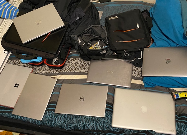 several stolen laptops displayed on a bed