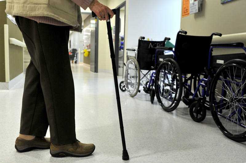 An elderly woman uses a walking stick to assist her mobility