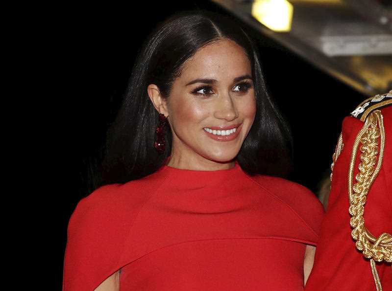 Wearing a red dress Meghan, Duchess of Sussex with Prince Harry arrives at the Royal Albert Hall in London