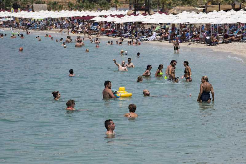 People swim during a heatwave at a beach, in Alimos suburb, southern Athens, Greece