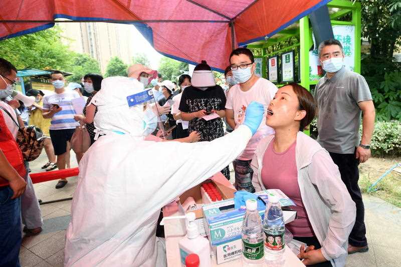 A medical worker takes samples for the mass Covid-19 test in a residential block in Wuhan, Hubei province, China, 3 August 2021