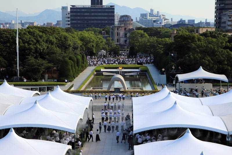 People attend a ceremony in front of a cenotaph at Peace Memorial Park in Hiroshima to mark the 76th anniversary of the bombing of Hiroshima.