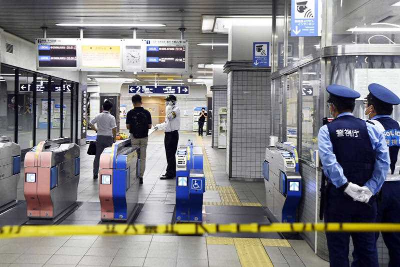 2 Policemen stand as ticket gates are sealed off at Soshigaya Okura Station after stabbing on a commuter train, in Tokyo