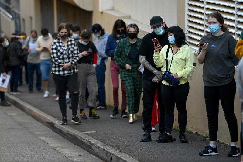 People wearing face masks line up for their COVID-19 vaccination at the NSW Health Walk-in AstraZeneca vaccination clinic in Glebe, Sydney