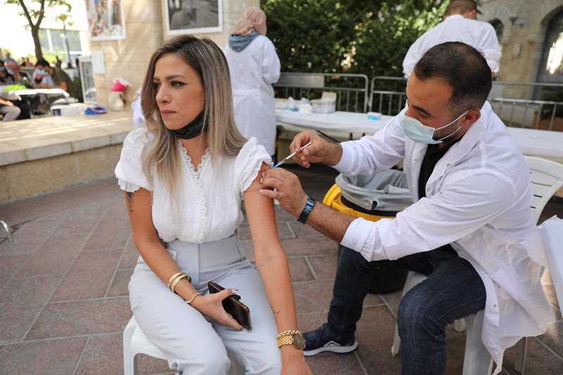 A nurse injects a women with a third shot of COVID-19 vaccine in Jerusalem, Israel, 25 August 2021